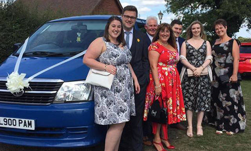 People ready for a wedding standing in front of pam's mini bus